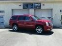 Red SUV parked outside a storefront with a blue awning