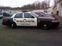 Police car parked in a lot with snow and other vehicles in the background