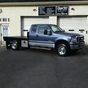 Blue pickup truck parked outside a building with open garage doors