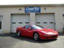 Red sports car parked in front of a garage with a sign above the doors