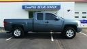 Gray pickup truck parked in front of a storefront with a sign above the entrance