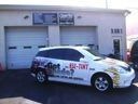 White taxi sedan parked in front of a garage door with company branding on the side.