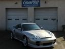 Silver sports car parked in front of a garage with a blue sign and two closed doors