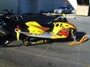 Yellow and black snowmobile on a trailer, outdoors