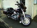 Black motorcycle parked indoors on a tiled floor, with chrome details and a white front wheel.