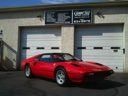 Red sports car parked in front of a garage with two white doors