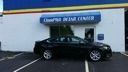 Black car parked outside a blue building with a sign above the door