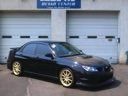 Black sedan with gold rims parked in front of a garage door