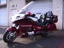 Red touring motorcycle parked in a driveway beside a garage.