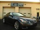 Dark sedan parked in front of a beige garage door with a sign above it