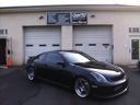 Black sports car parked in front of a garage with closed white doors