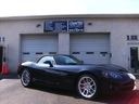 Black sports car parked outside a garage with lift doors