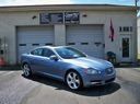 Blue sedan parked in front of a building with flags and garage doors