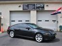 Dark gray coupe parked in front of a garage door and storefront with an American flag
