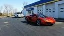 Red sports car parked beside a blue-and-white building on a sunny street.