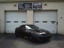 Black sports car parked in front of two white garage doors with signs above them