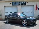 Black sports coupe parked in front of a garage with two white doors