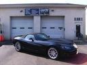 Black sports car parked in front of garage doors at a house