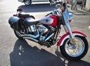 Red and black motorcycle parked on pavement in bright sunlight.