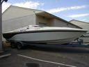 White speedboat on a trailer parked beside a house and driveway