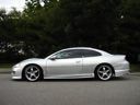 Silver sports coupe parked on a road, side view