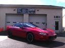 Red sports car parked in front of a garage with closed doors