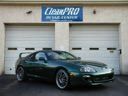 Green sports car parked outside a garage with a blue sign above the doors