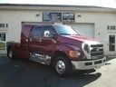 Maroon pickup truck parked in front of a building, viewed from the front-left side