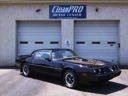 Black sports car parked in front of two garage doors under an auto shop sign