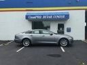Silver coupe parked in front of a blue auto center storefront