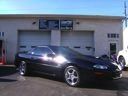 Black sports car parked outside a garage on a sunny day
