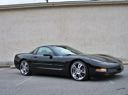 Gray sports car parked on a road, side view against a plain light background