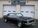 Black classic sports car parked in front of a garage with white doors