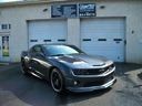Black sports car parked in front of a garage with blue doors