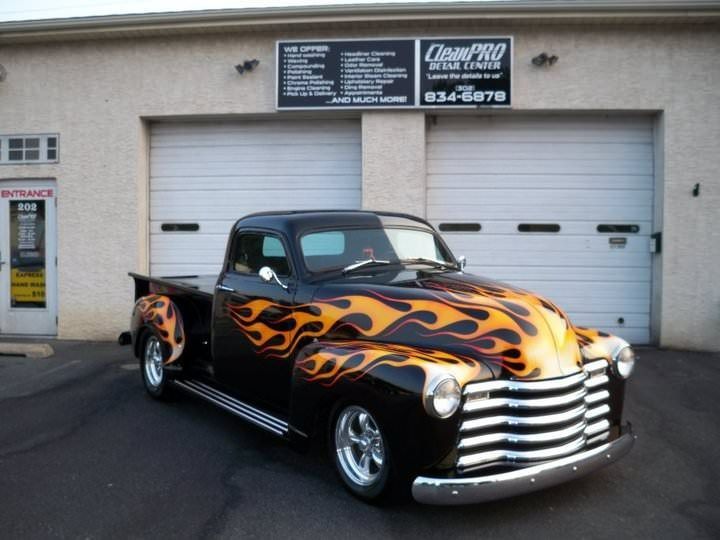 Custom black pickup truck with orange flame graphics parked in front of garage doors