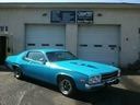 Turquoise classic car parked in front of a garage