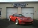 Red sports car parked in front of a garage with closed white doors