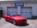 Red sports car parked in front of a garage with a sign above it