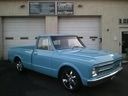 Light blue classic pickup truck parked in front of a garage