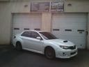 Silver sedan parked in front of a garage with closed white doors