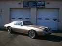 Silver sports car parked in front of a garage with closed blue doors