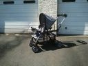 Empty stroller in driveway beside a garage door, casting a long shadow.