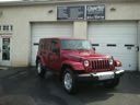 Red Jeep parked outside a building with garage doors on a snowy street