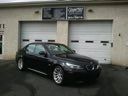 Black sedan parked in front of a white garage door and storefront windows