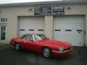 Red sports car parked in front of a beige garage with two doors