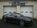 Black sedan parked in front of a garage with white doors and beige walls