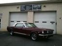 Maroon classic car parked in front of a garage with white doors