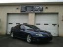 Dark blue sports car parked in front of a beige garage with two white doors