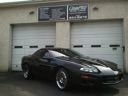 Black sports car parked in front of a garage with closed doors