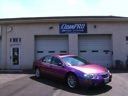 Purple car parked outside a garage with a sign above the doors